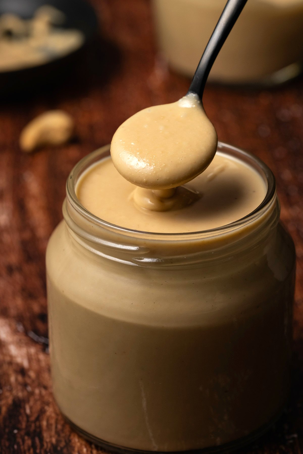 Cashew butter in a glass jar with a spoon. 