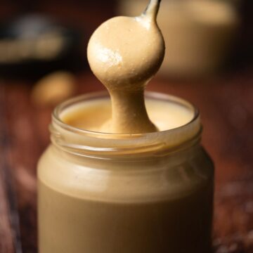 Cashew butter in a glass jar with a spoon.
