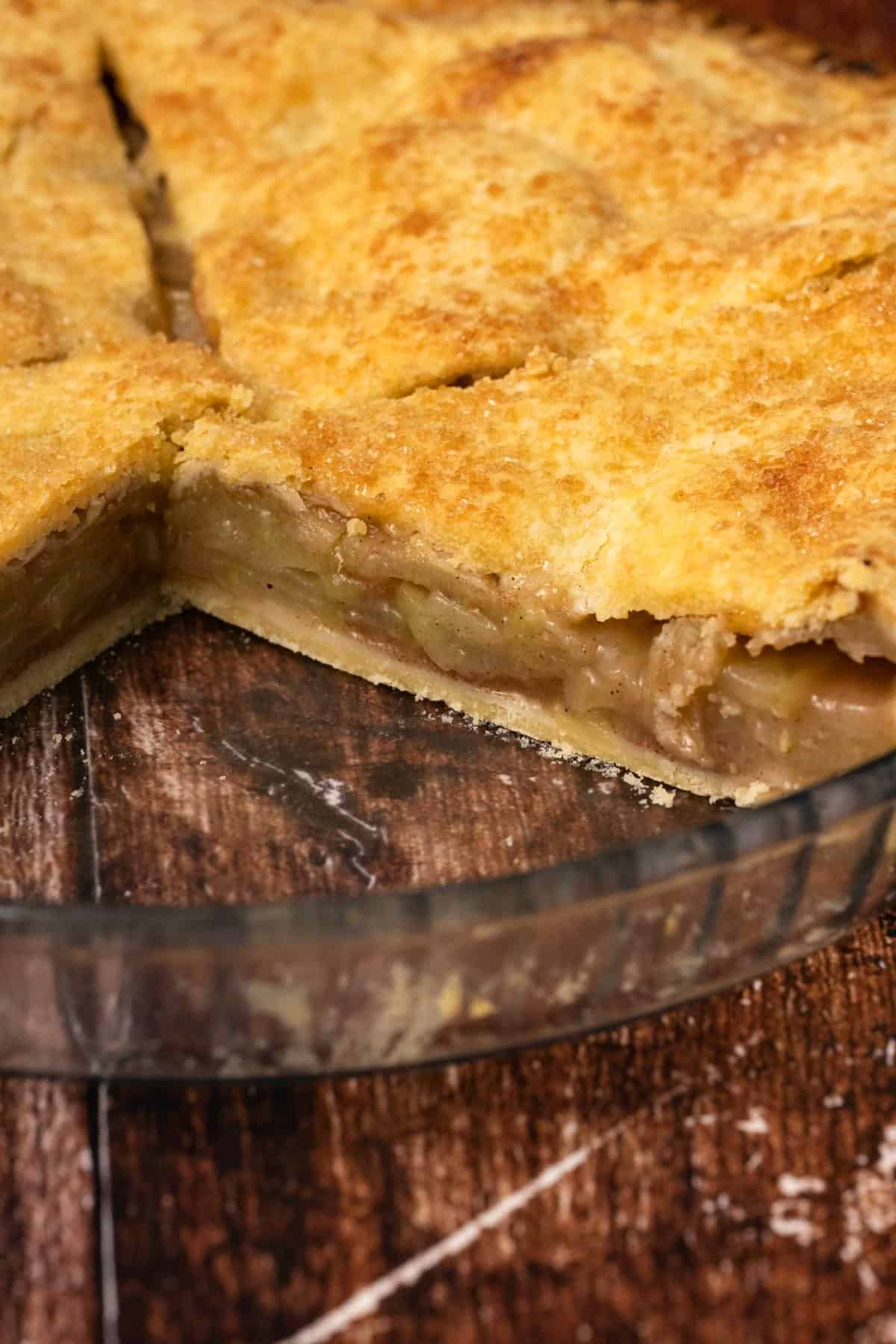 Apple pie in a glass pie dish with two slices removed.
