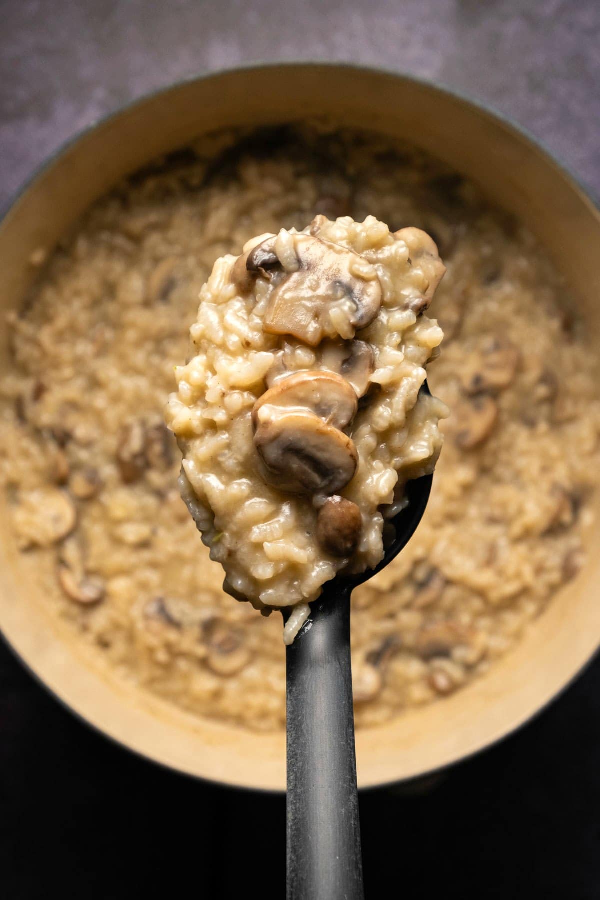 Vegan mushroom risotto in a pot with a serving spoon.
