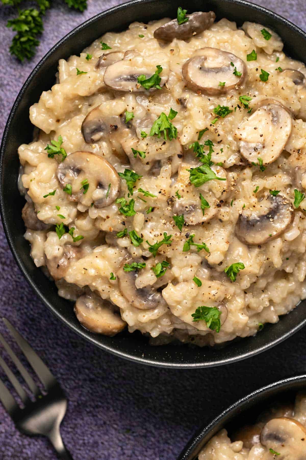 Vegan mushroom risotto topped with fresh chopped parsley and ground black pepper. 