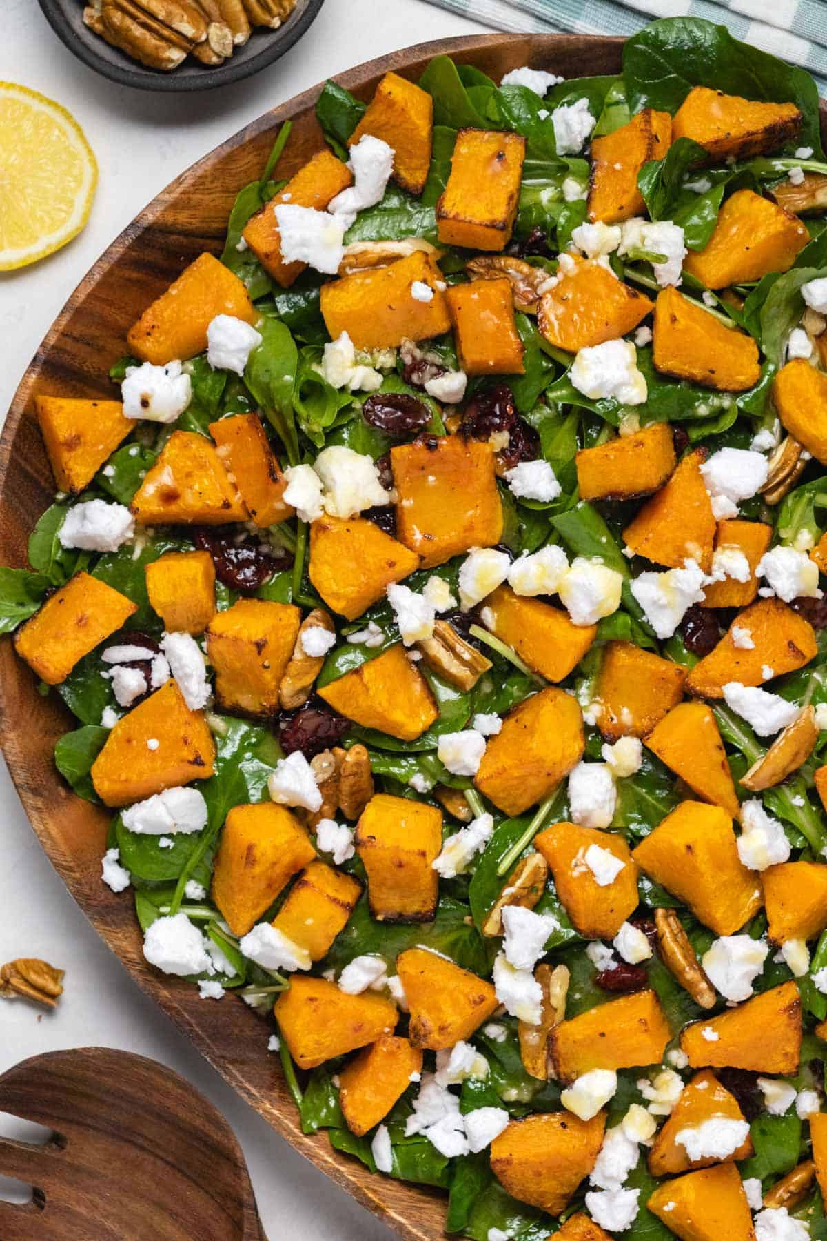 Butternut squash salad with pecans and cranberries in a wooden salad dish. 