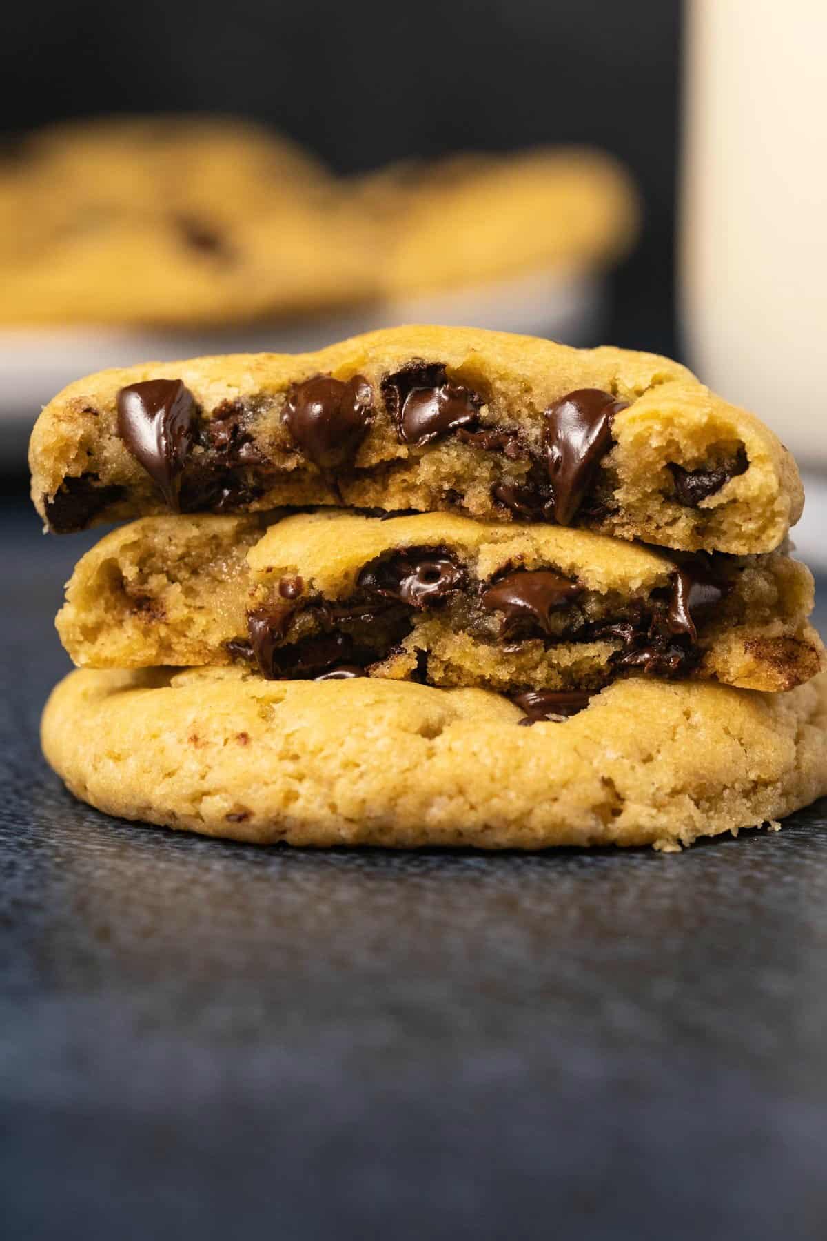 Stack of two vegan chocolate chip cookies with the top cookie broken in half. 