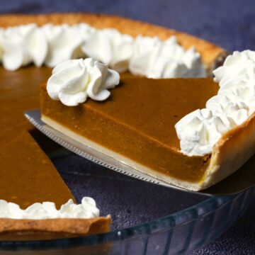 Vegan pumpkin pie in a glass pie dish with one slice cut and ready to serve.