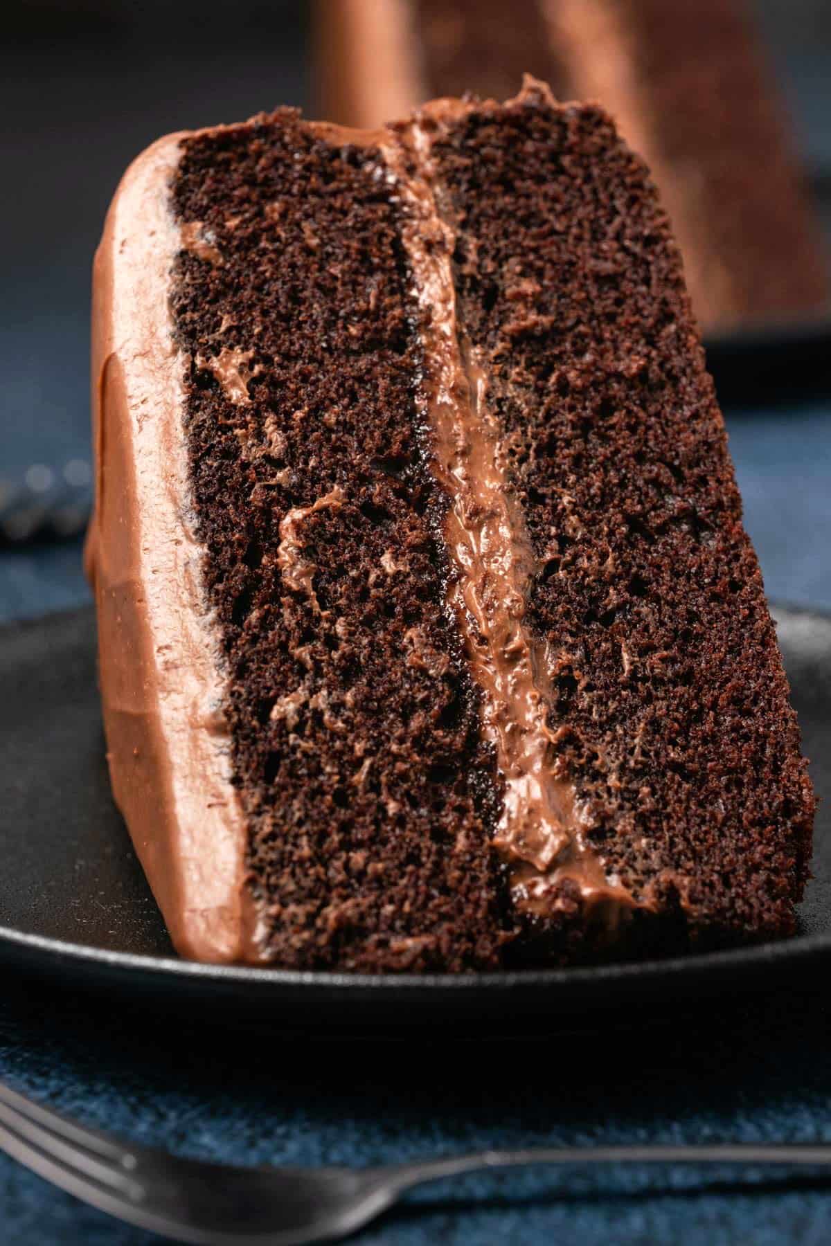 Slice of vegan gluten free chocolate cake on a black plate. 