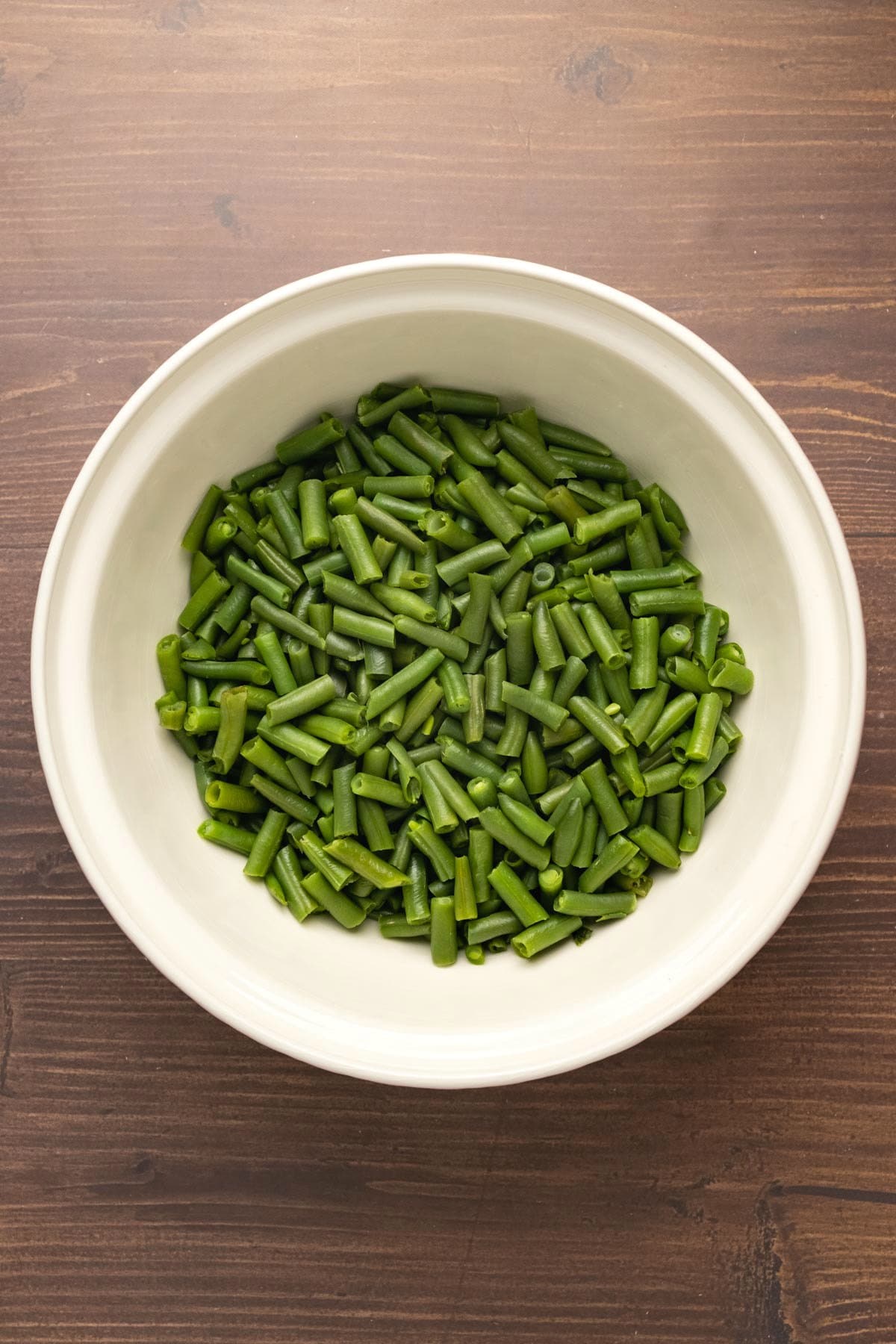 Cooked green beans in a white bowl. 