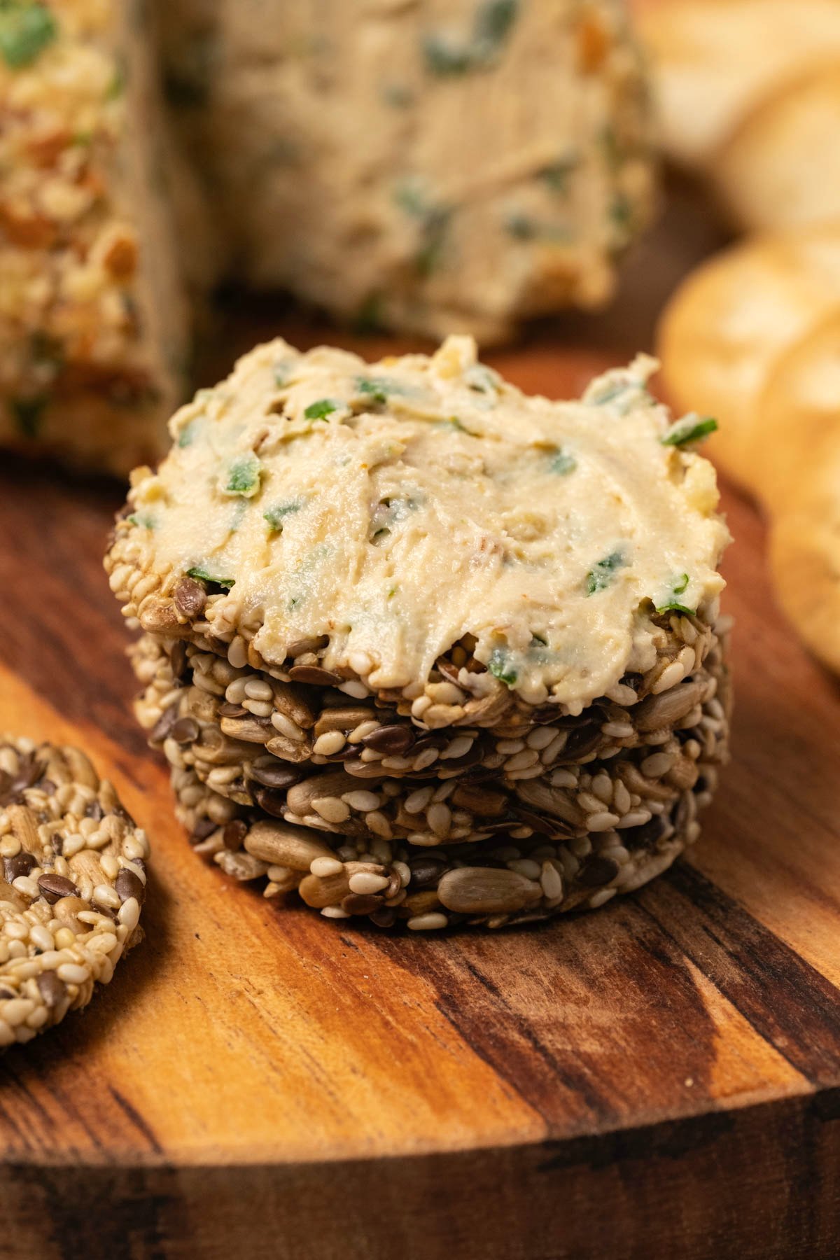 Stack of seed crackers spread with vegan cheese. 