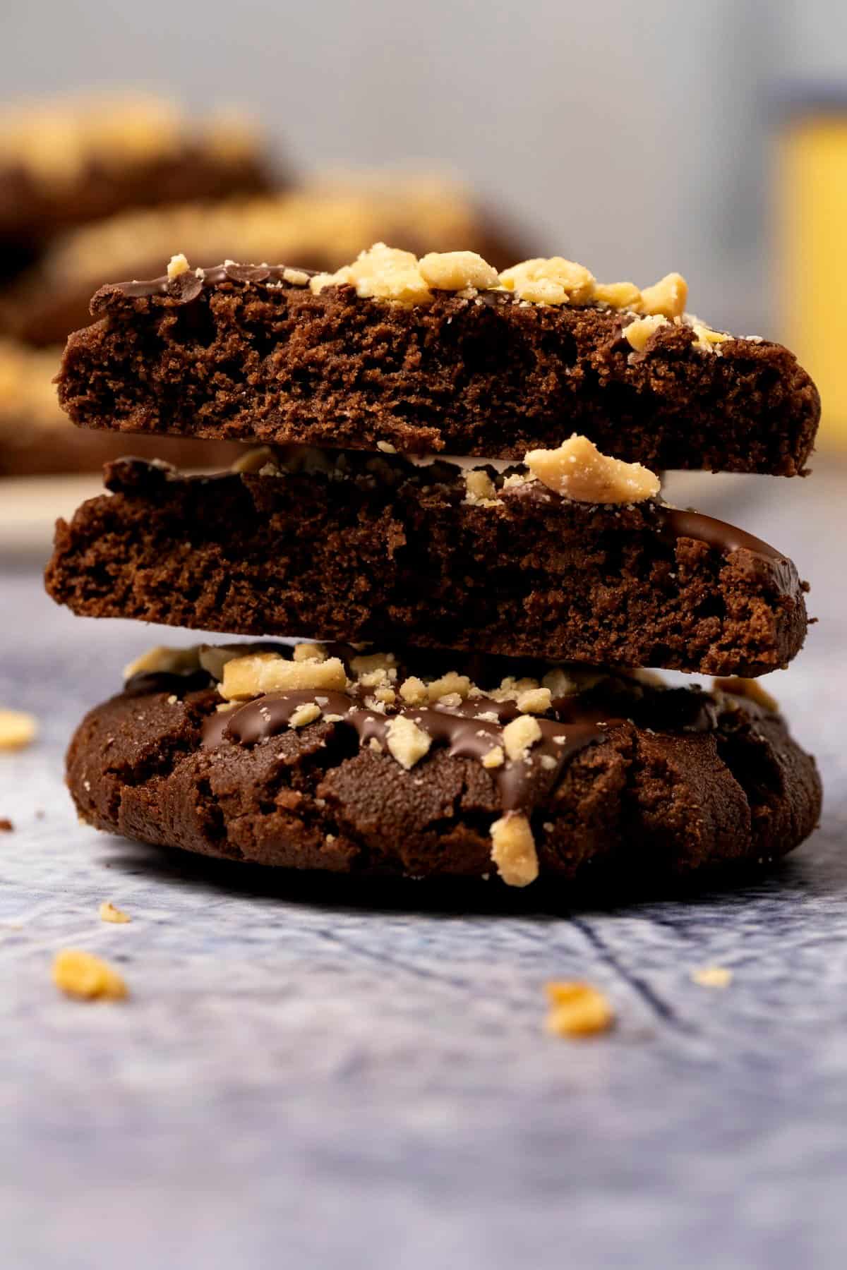 Vegan chocolate peanut butter cookies in a stack with the top cookie broken in half. 