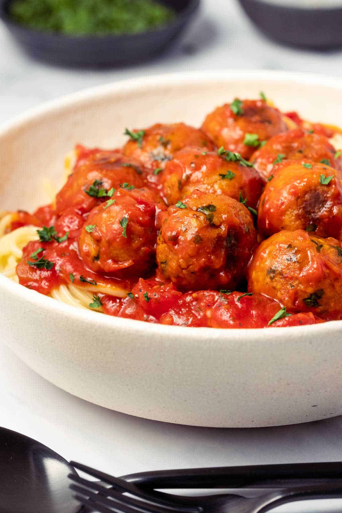 Chickpea meatballs with marinara sauce and spaghetti in a white bowl.
