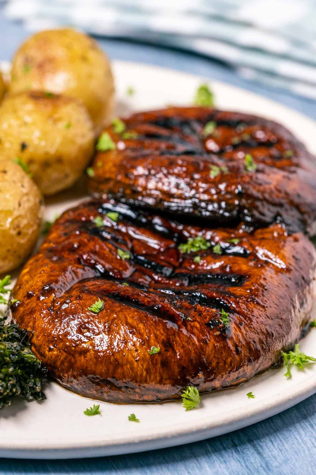 Portobello steaks on a plate with baby potatoes and broccoli. 