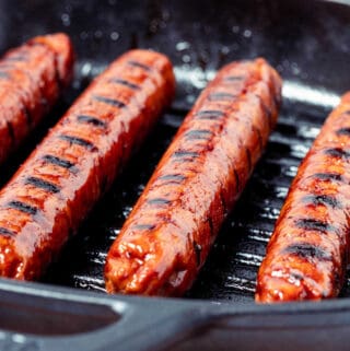 Close up photo of vegan sausages in a grill pan.