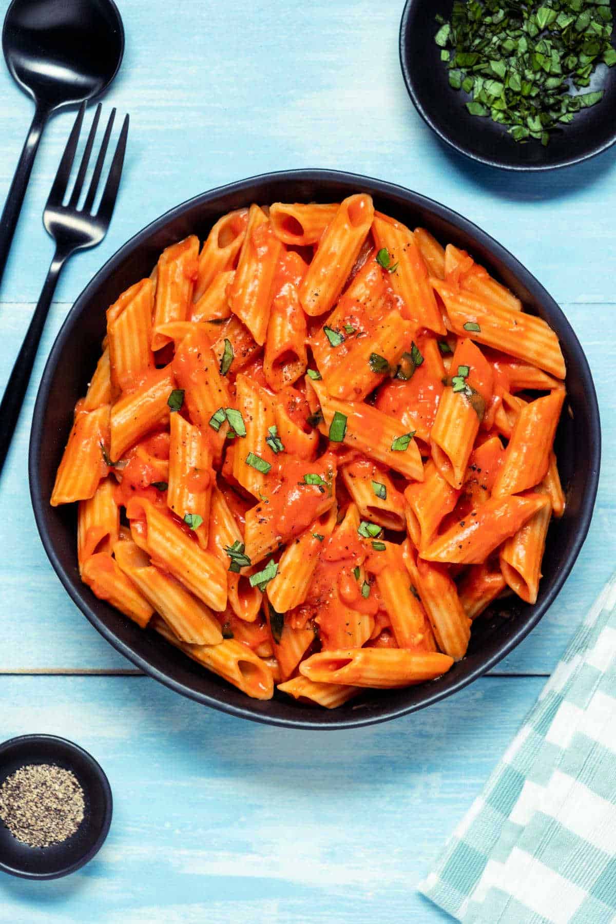 Penne and vegan vodka sauce in a black bowl.