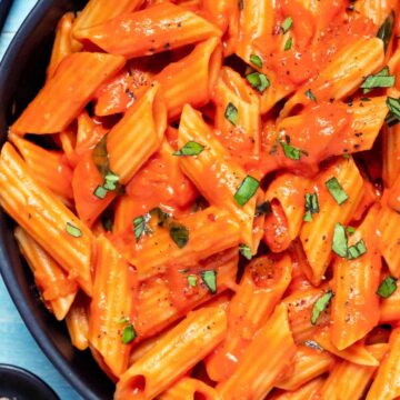 Penne and sauce in a black bowl.