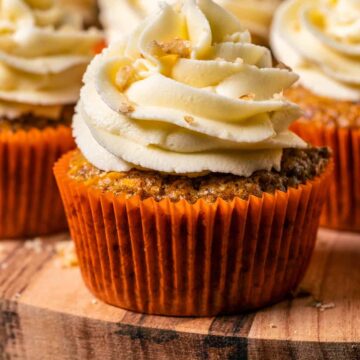 Vegan carrot cake cupcakes on a wooden board.