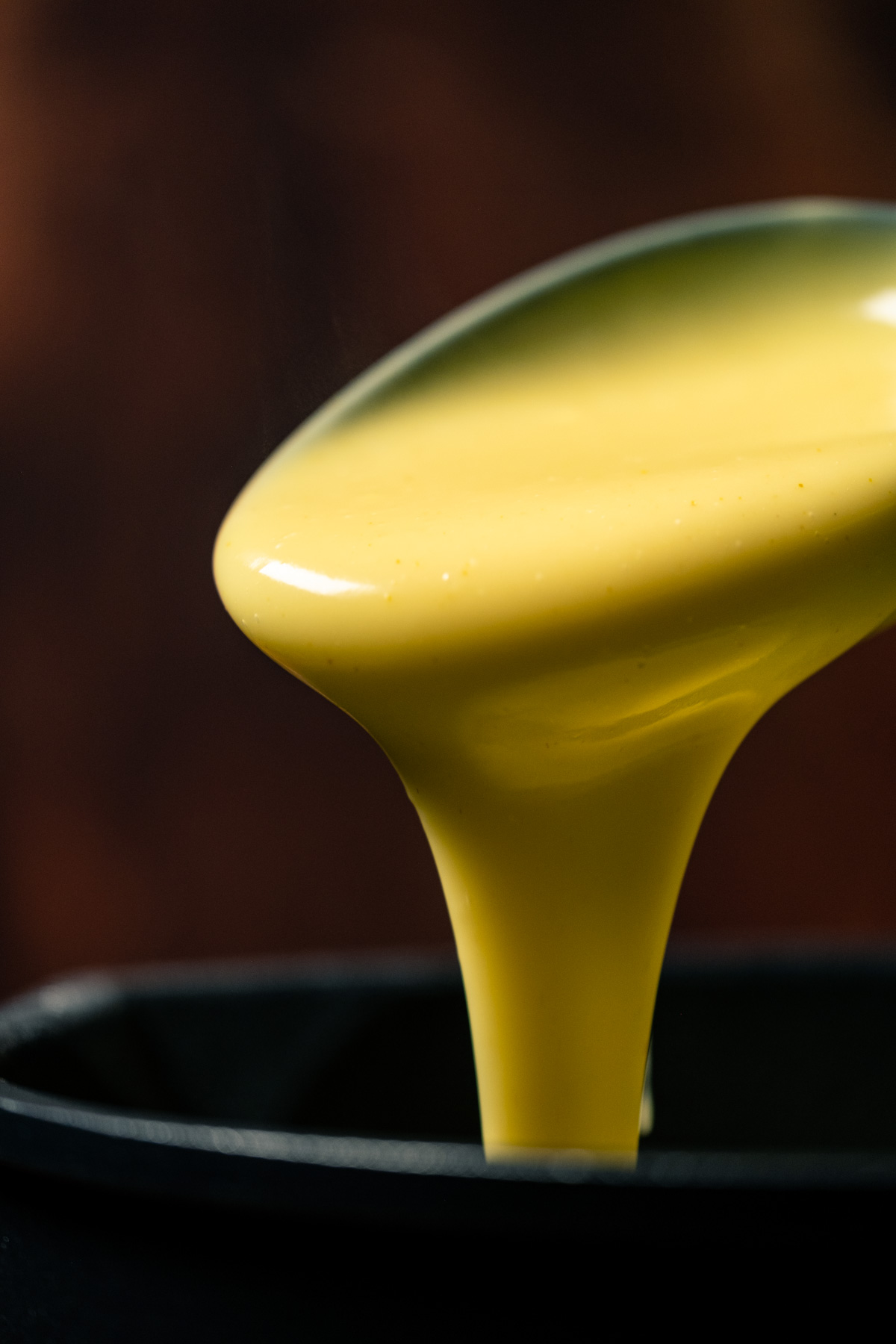 Custard pouring off a serving spoon.