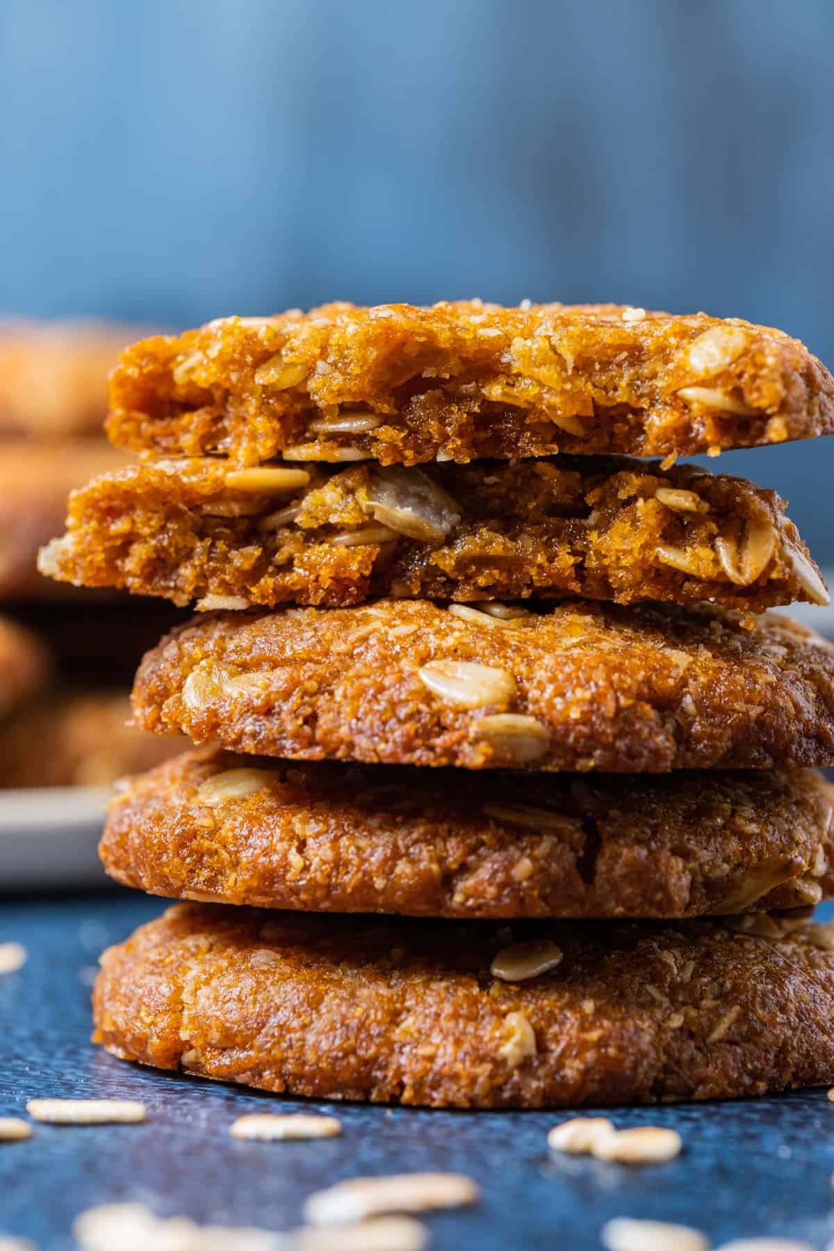 Vegan Anzac biscuits in a stack with the top biscuit broken in half.