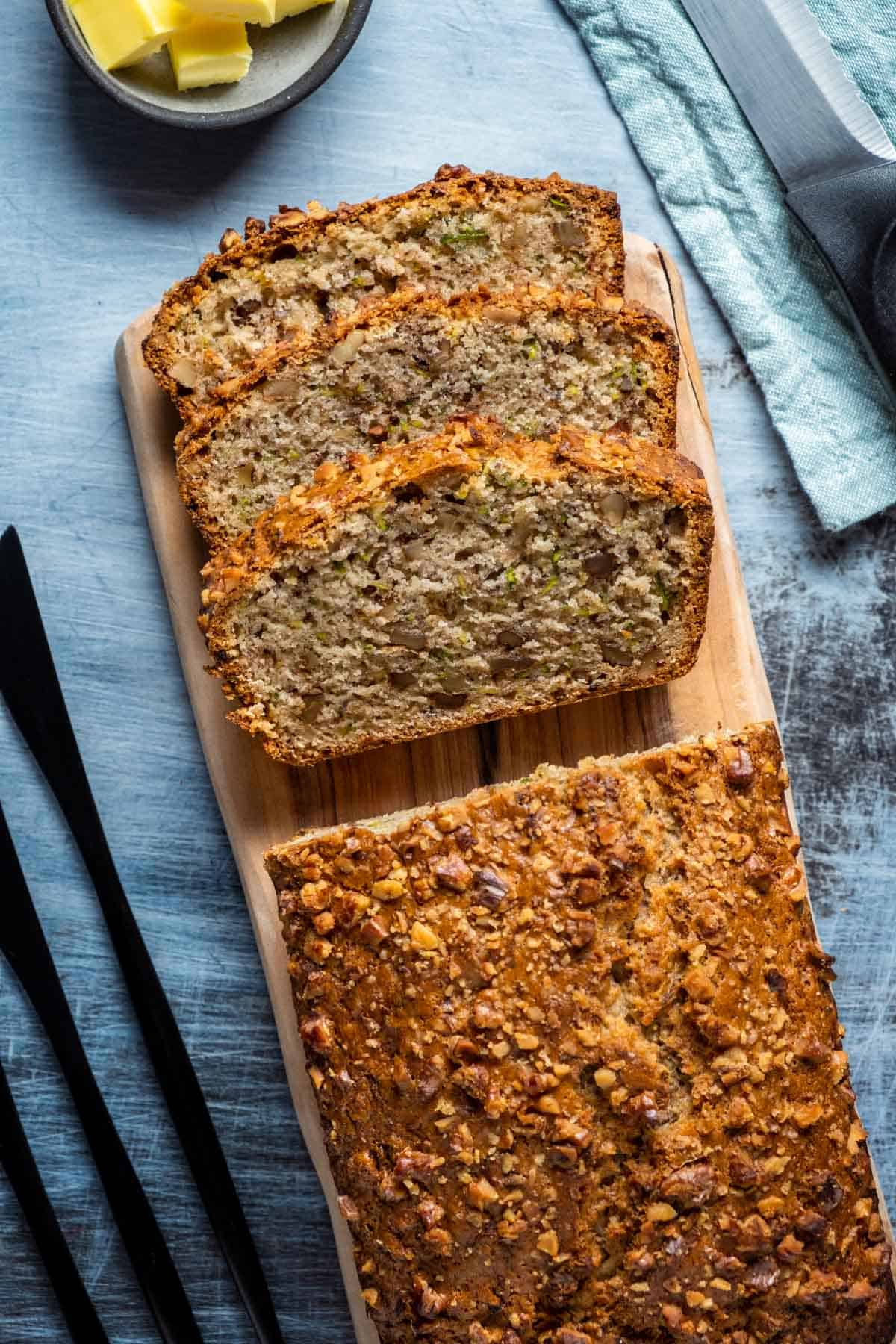 Sliced loaf of vegan zucchini bread on a wooden board. 