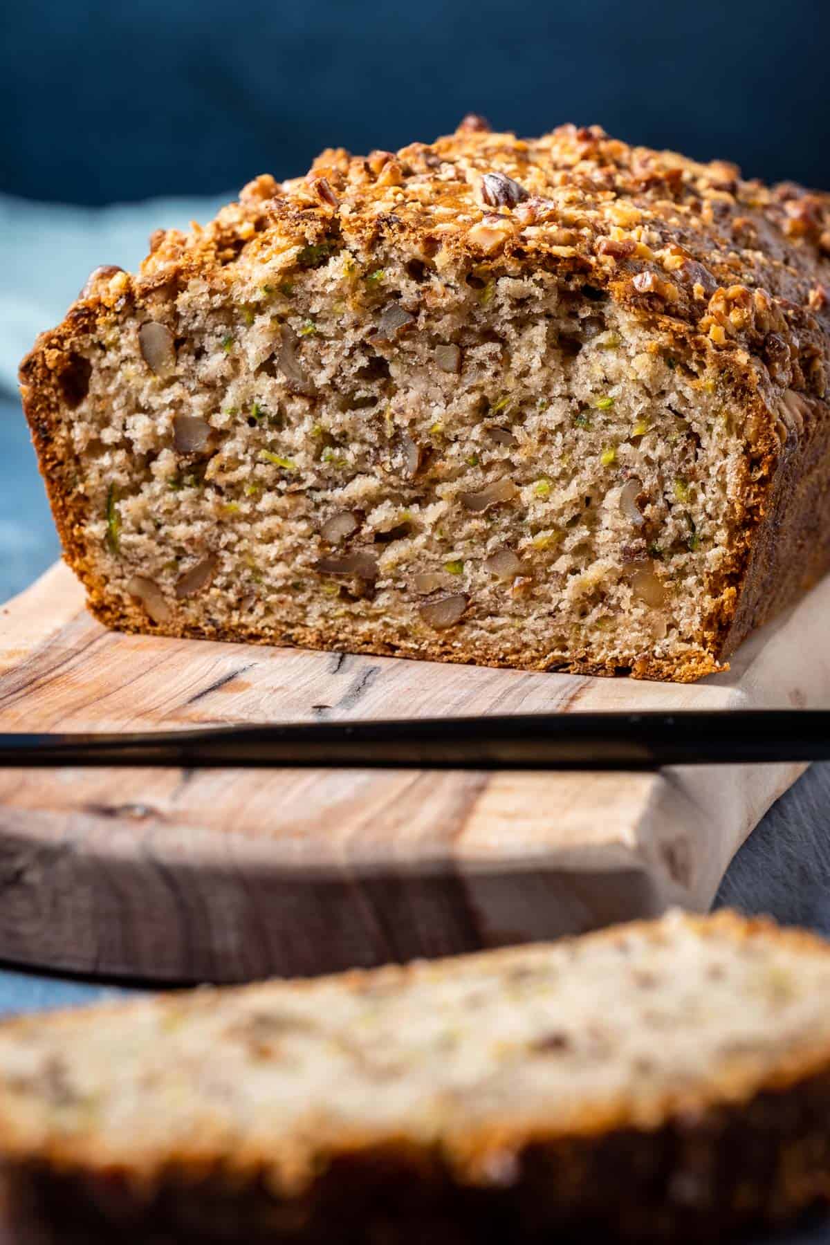 Loaf of vegan zucchini bread on a wooden board.