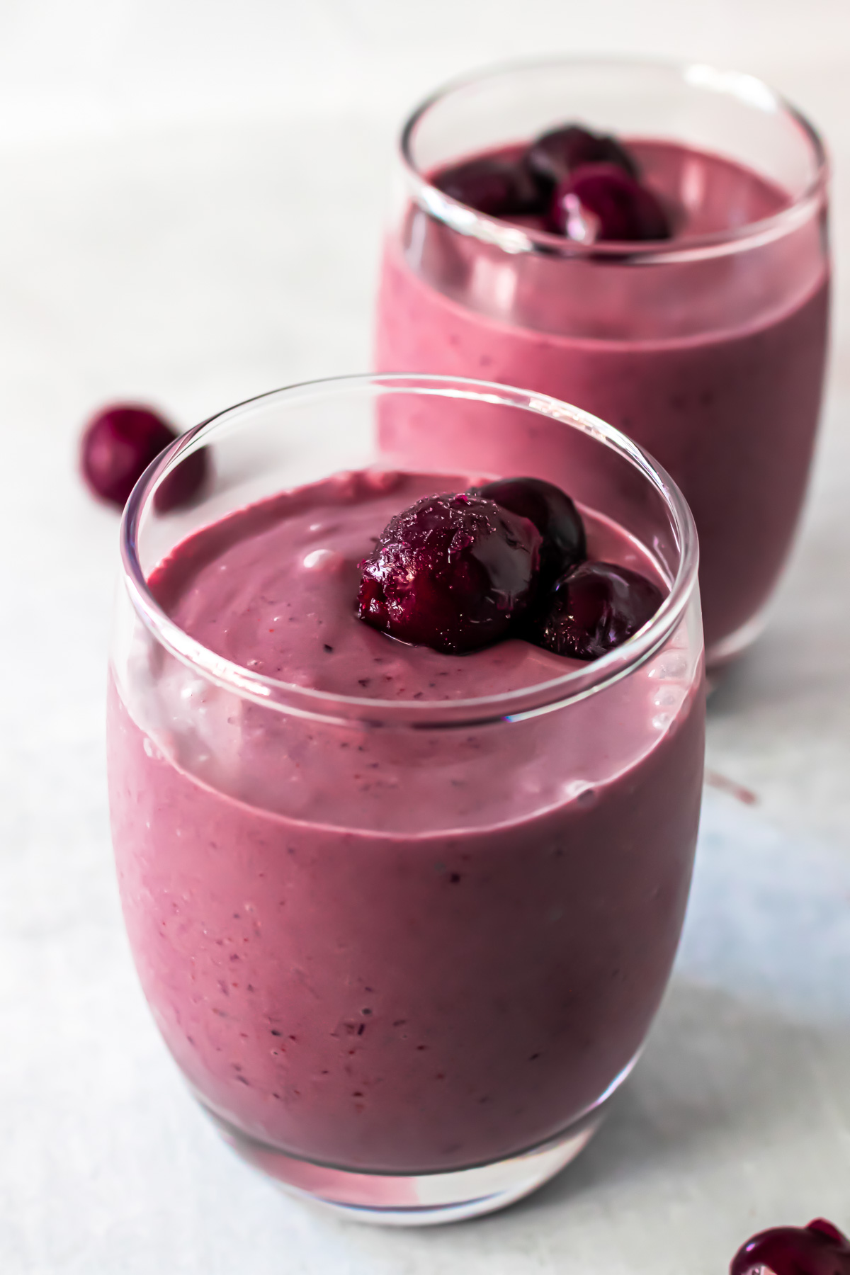 Smoothie topped with cherries in two glasses. 
