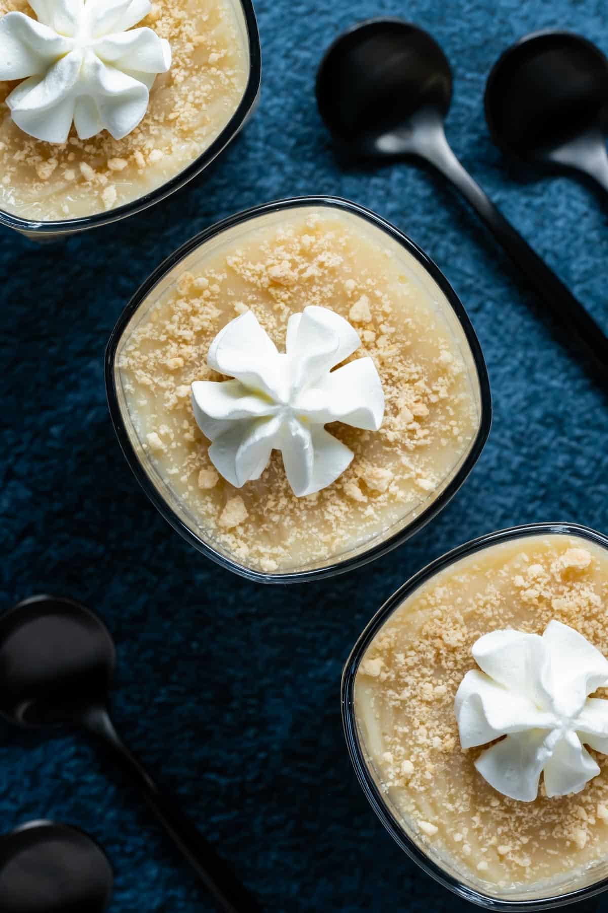 Vegan vanilla pudding topped with vegan cream in small glasses.