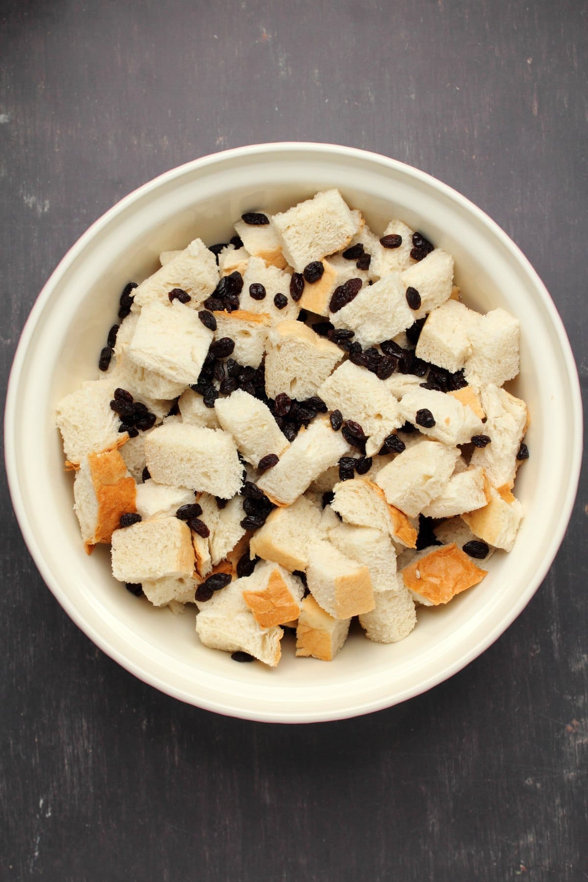 Cubes of bread with raisins in a white bowl. 