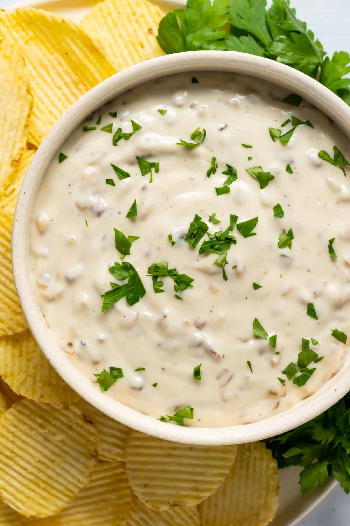 Vegan French onion dip topped with fresh parsley in a white dish.