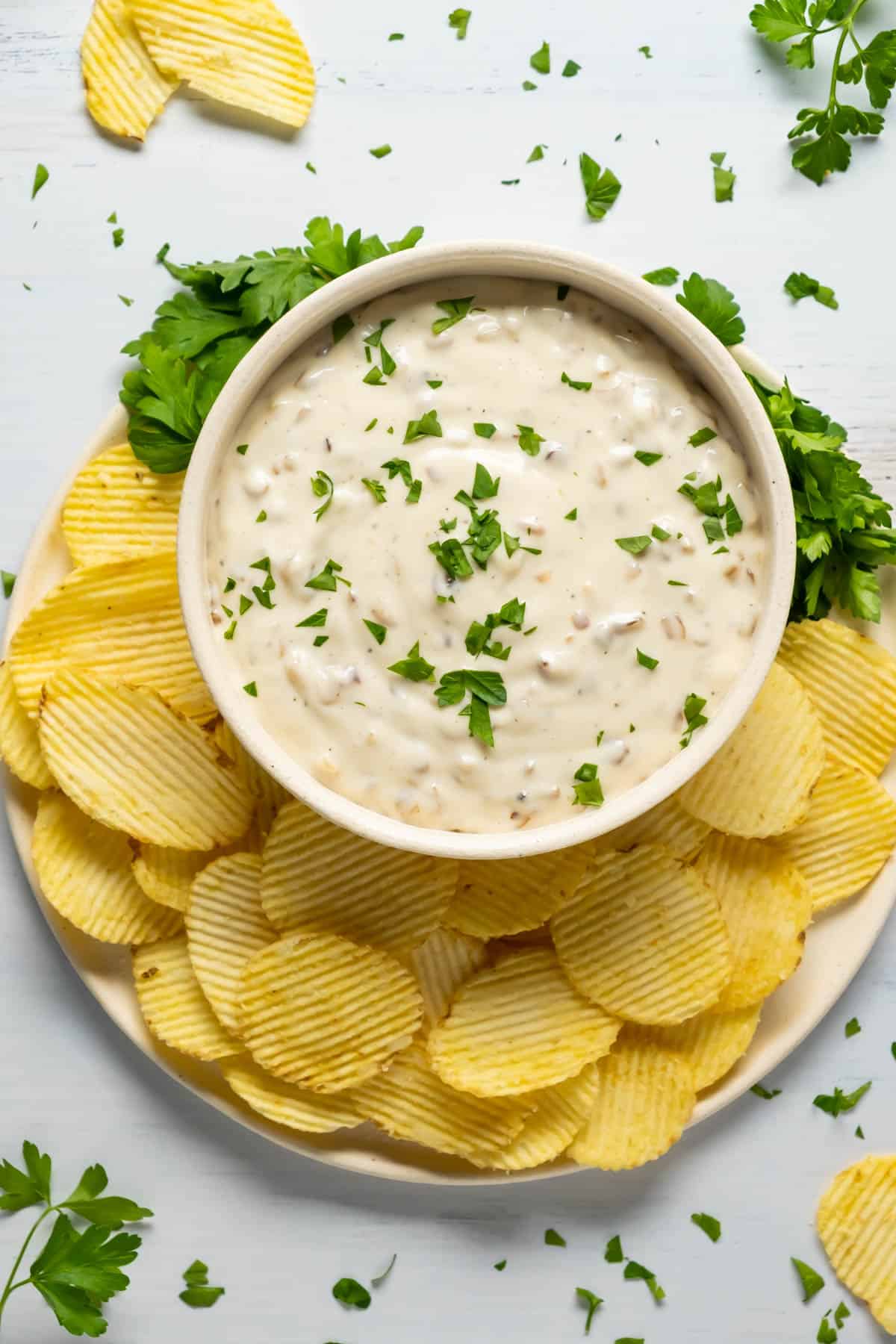 Vegan French onion dip topped with fresh parsley in a white bowl.