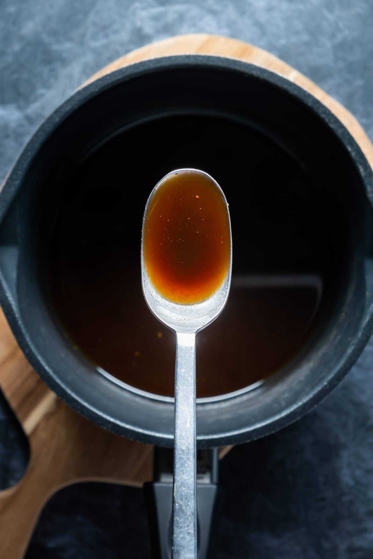 Vegan worcestershire sauce in a saucepan with a spoon.