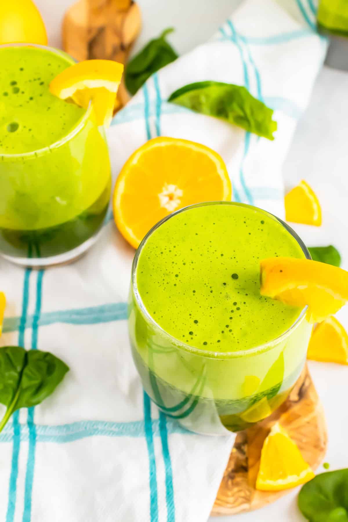 Green juice in glasses with orange slices.