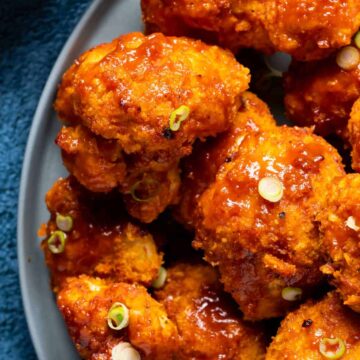 BBQ cauliflower wings on a plate with chopped spring onions.