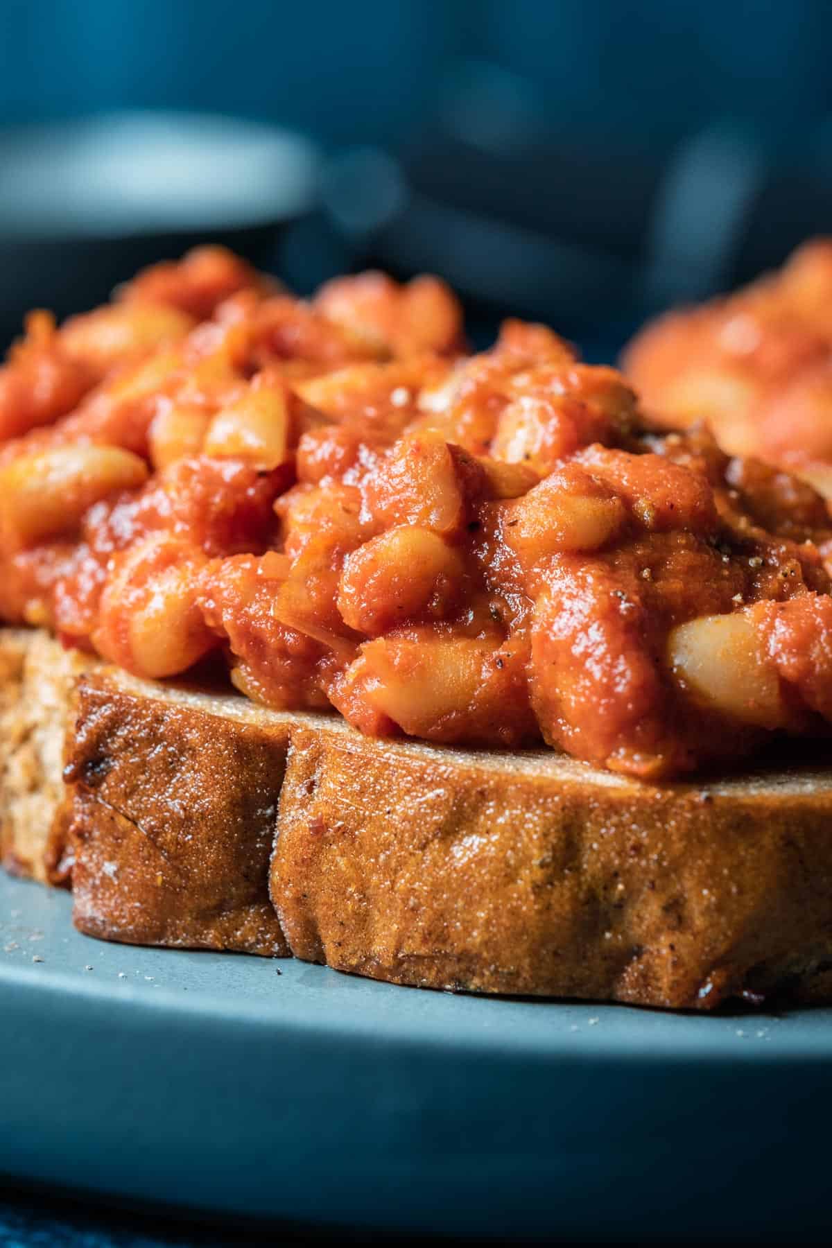 Toast topped with baked beans on a blue plate.