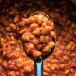 Vegan baked beans in a pot with a serving spoon.