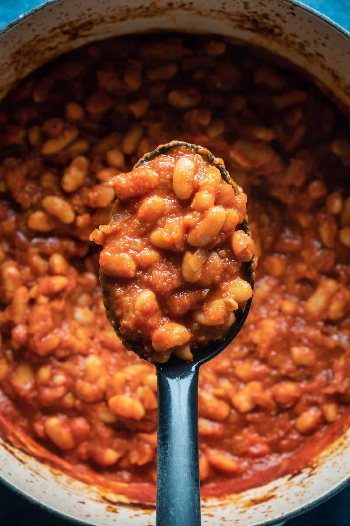 Vegan baked beans in a pot with a serving spoon.