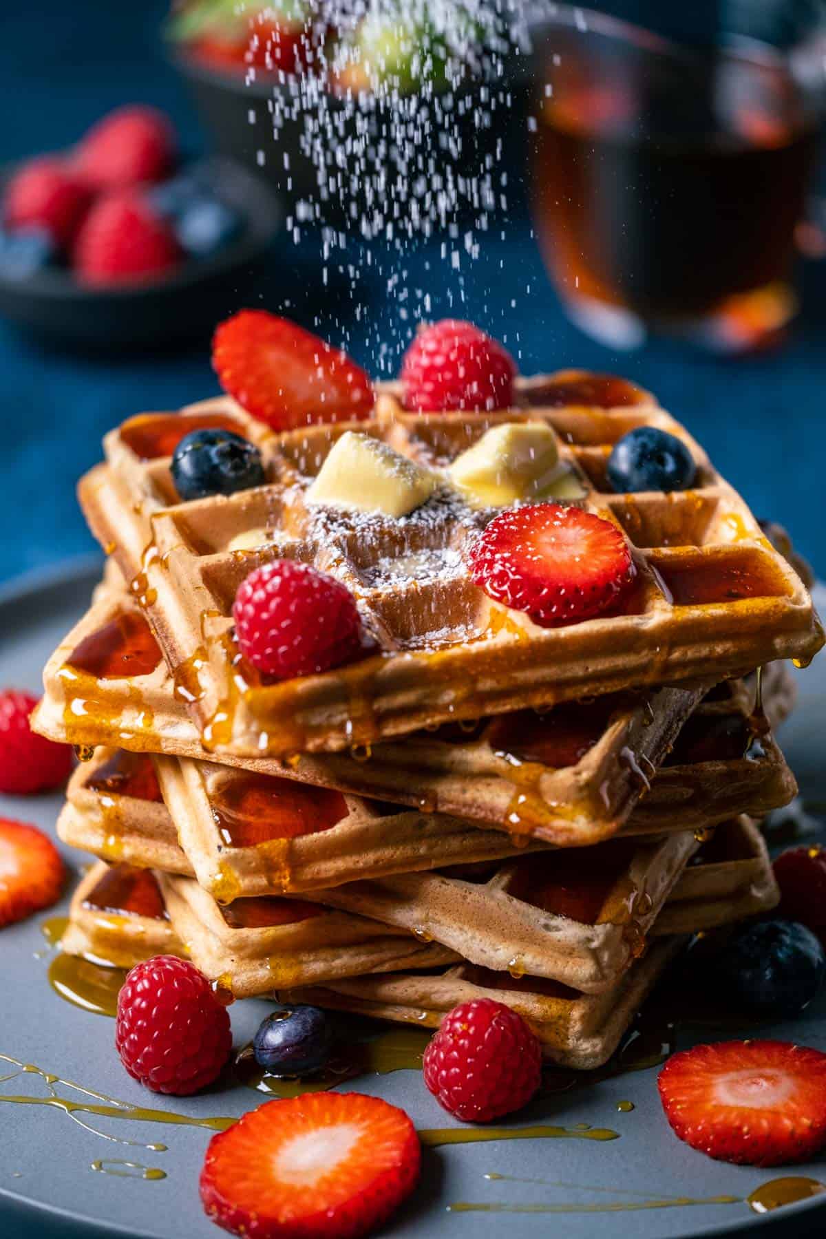 Powdered sugar sprinkling over a stack of vegan waffles.