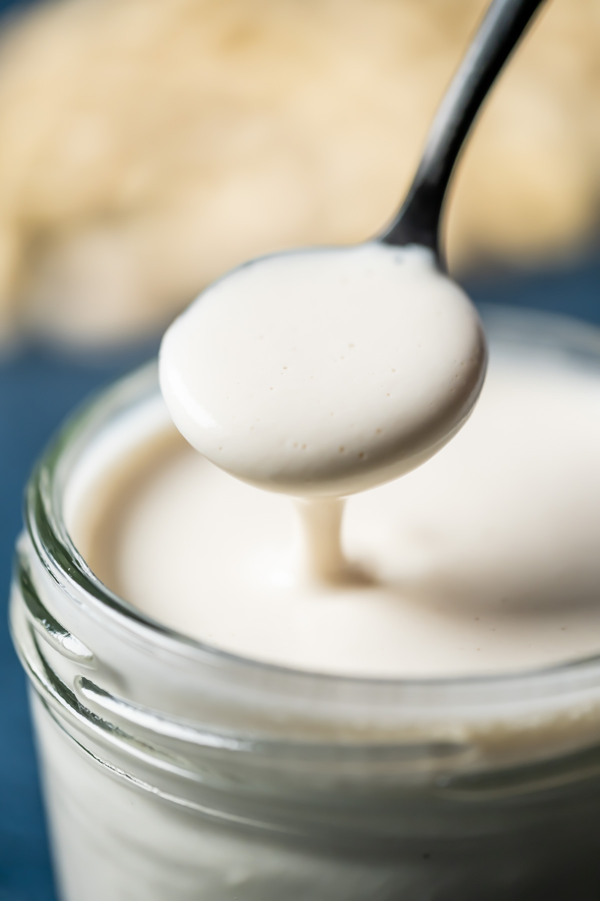 Vegan heavy cream substitute in a glass jar with a spoon.