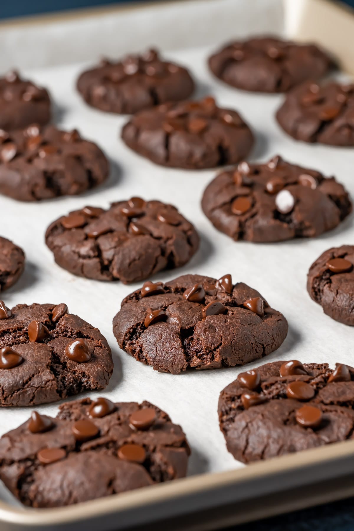 Vegan chocolate cookies on a parchment lined baking tray.