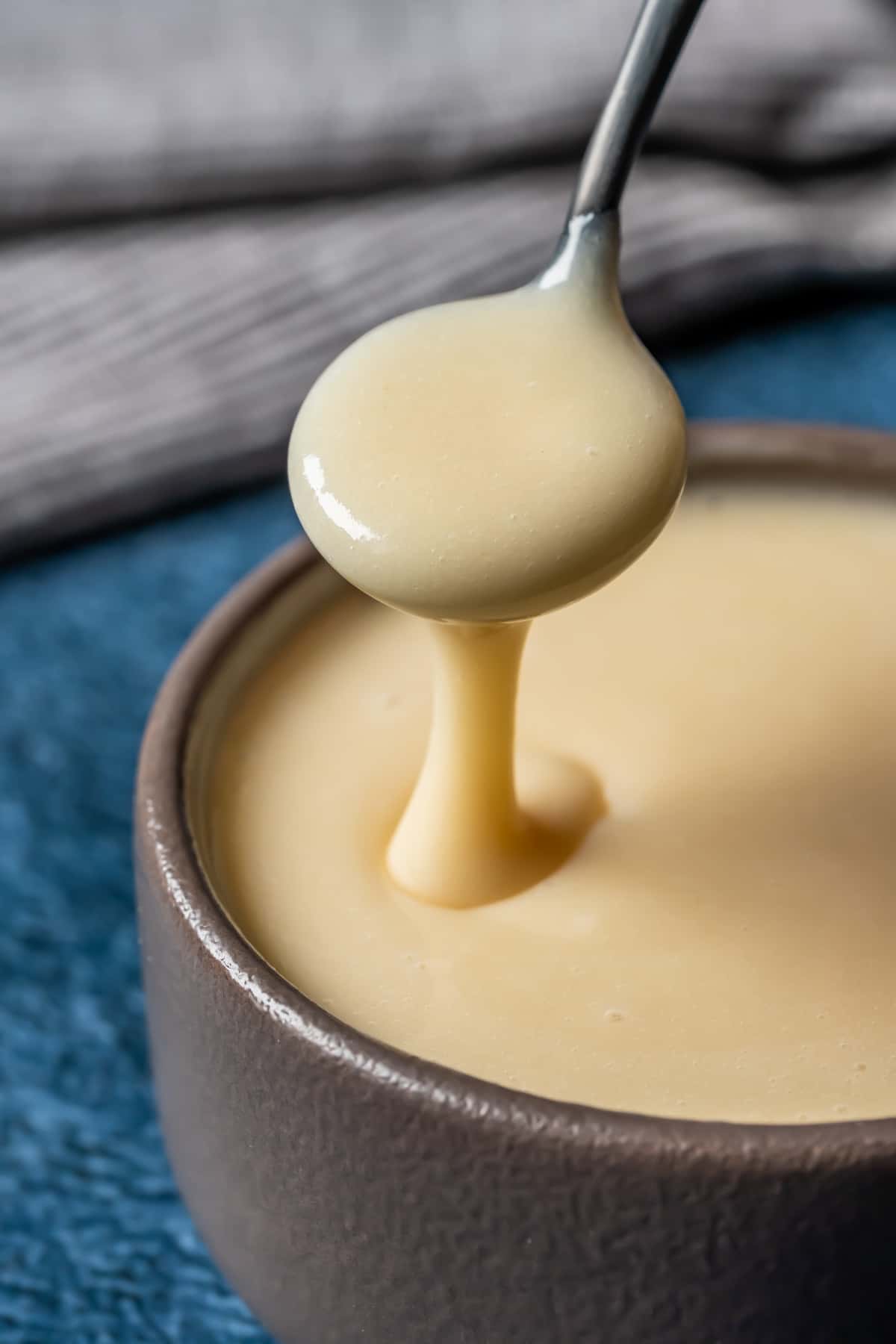 Vegan condensed milk in a brown bowl with a spoon. 