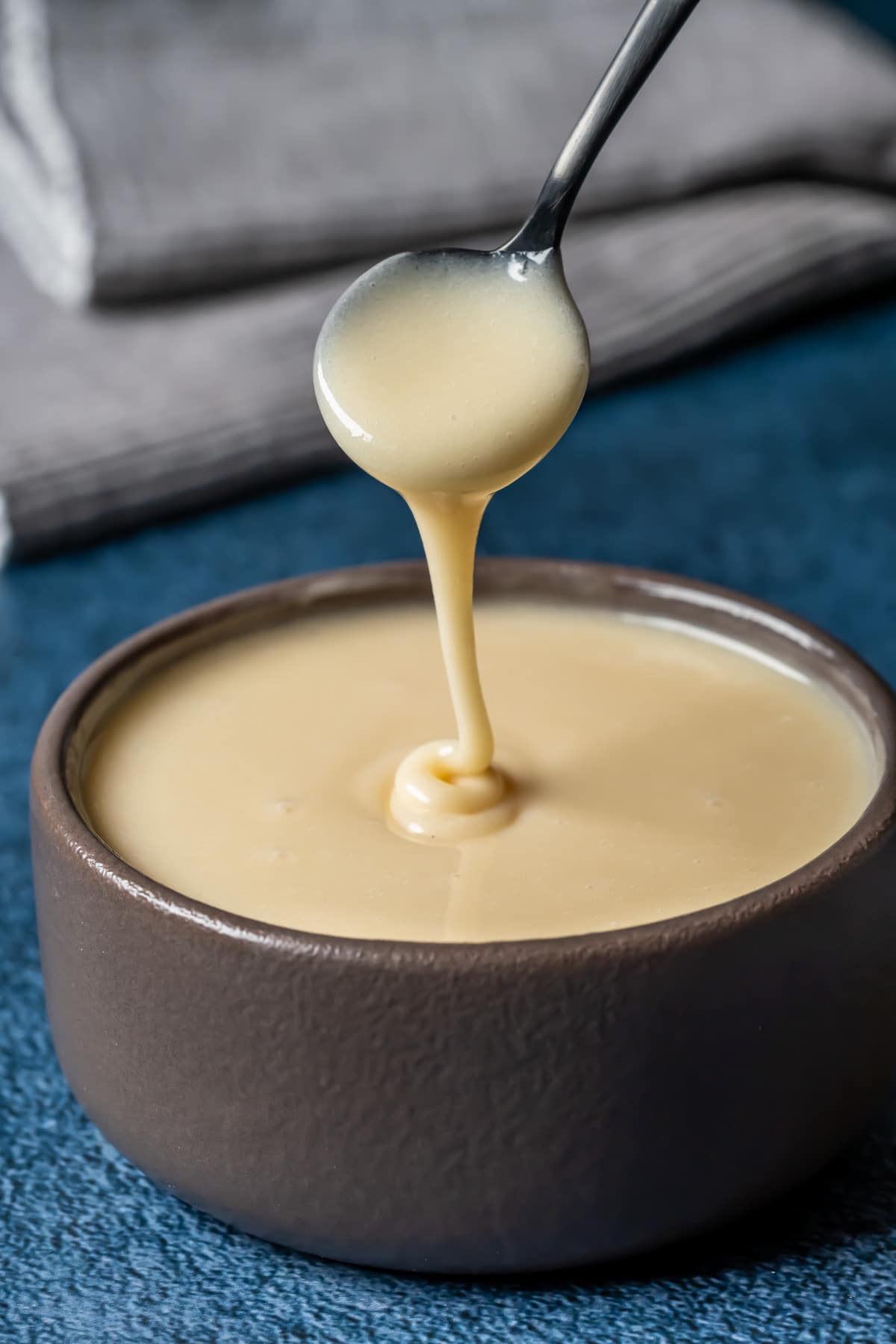 Vegan condensed milk in a brown bowl with a spoon.