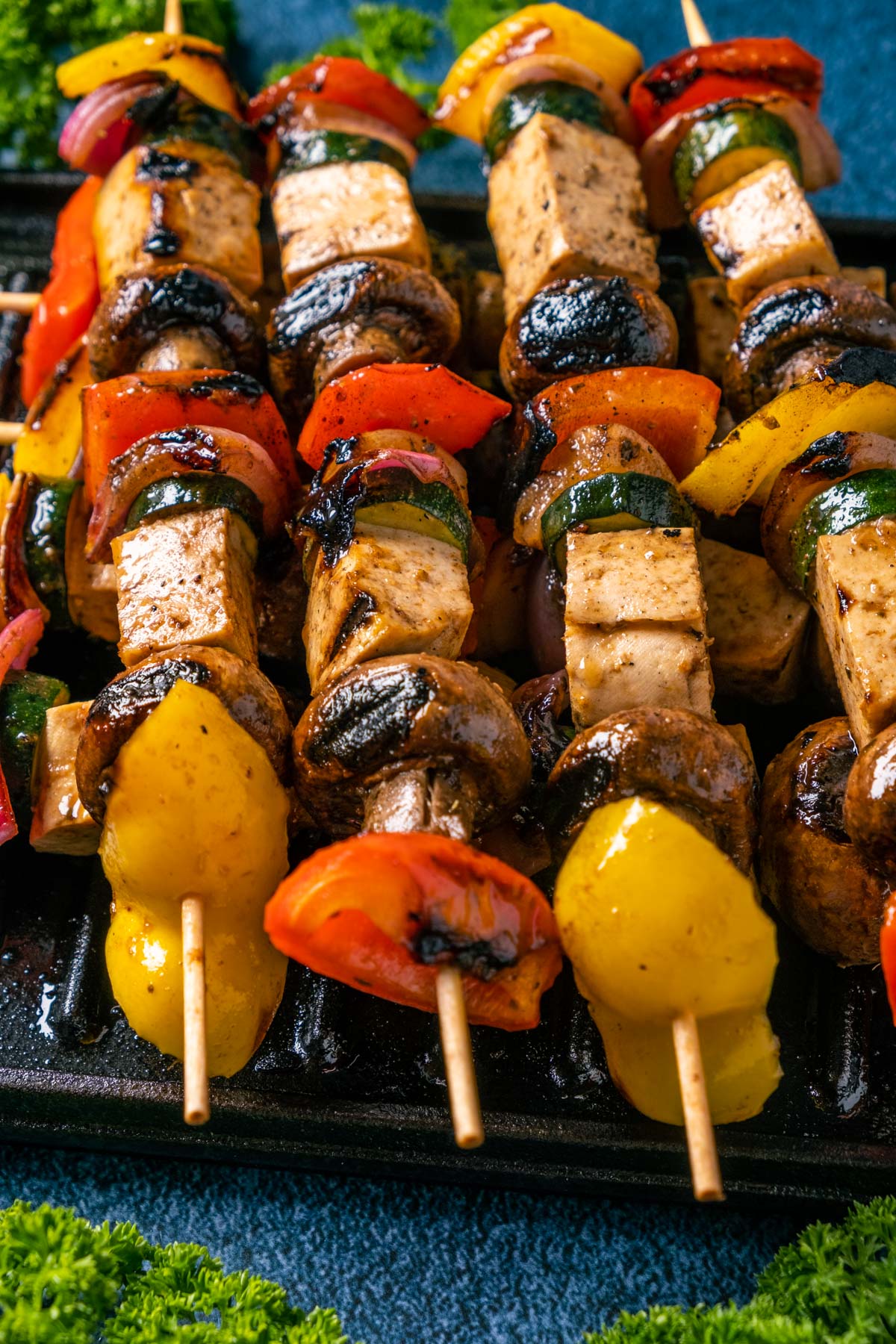 Vegan kebabs stacked up on a grill.