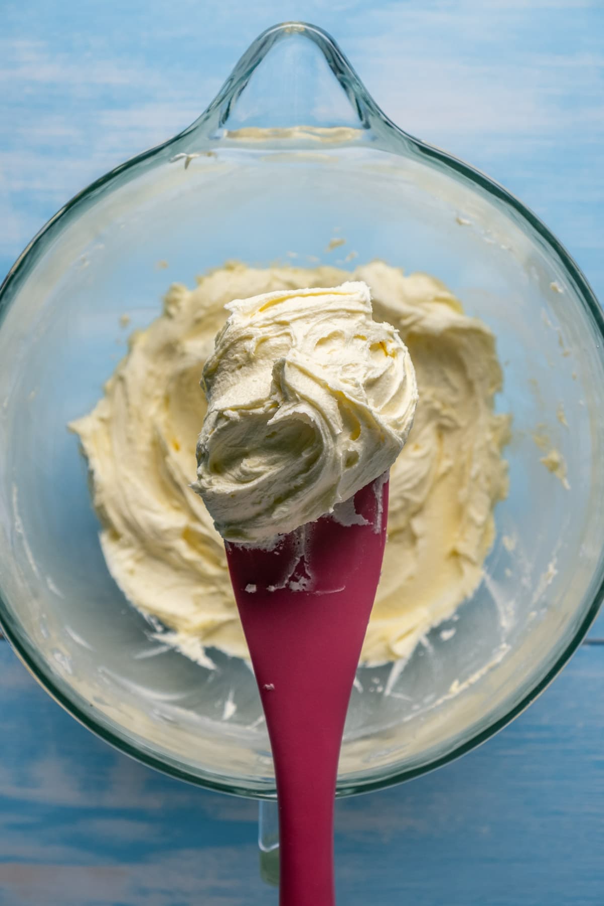 Vegan lemon frosting in a stand mixer with a spatula.