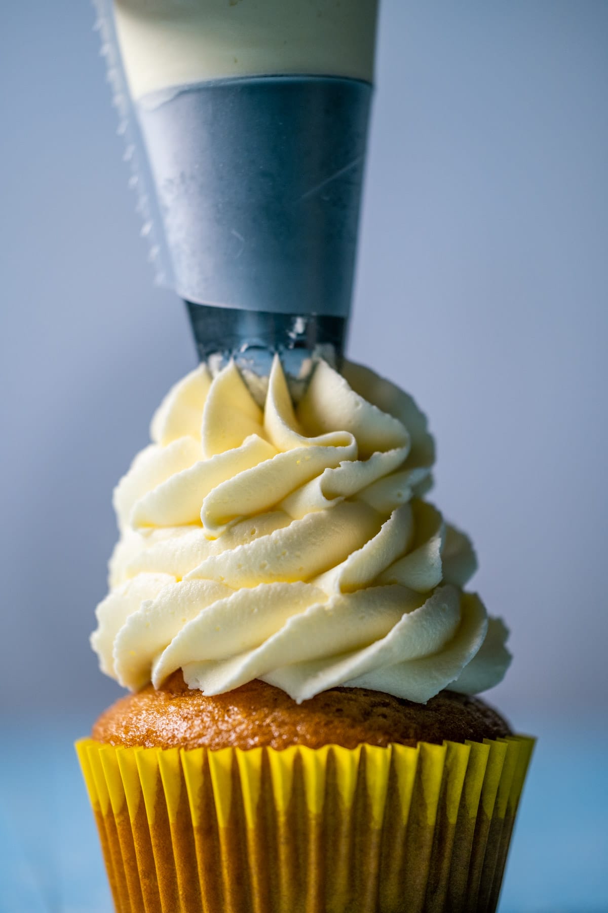Vegan lemon buttercream frosting piping onto a cupcake.