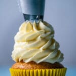 Vegan lemon frosting piping onto a cupcake.