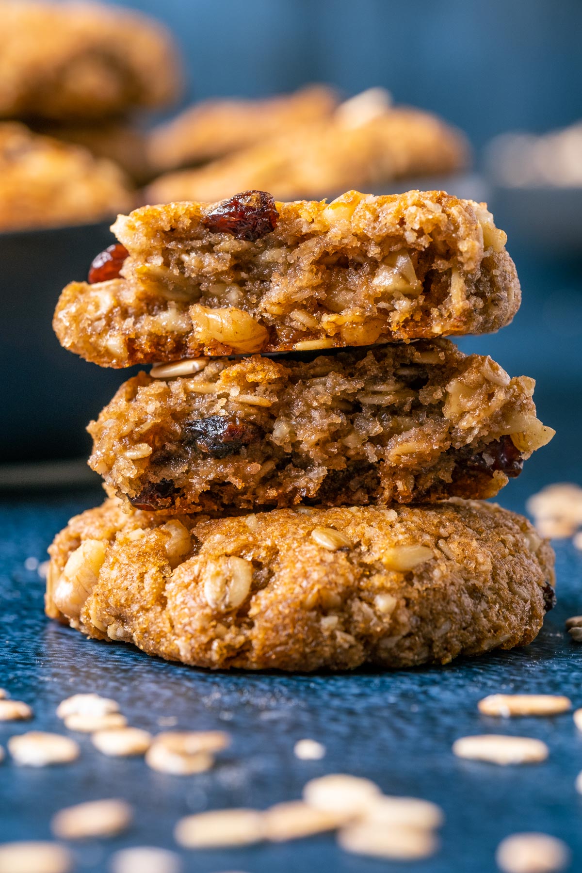 Vegan oatmeal raisin cookies in a stack with the top cookie broken in half.