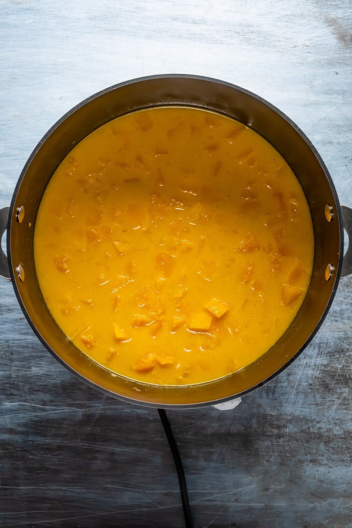 Vegan pumpkin curry cooking in a pot.