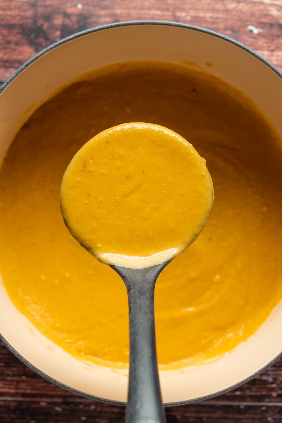 Vegan lentil soup in a pot with a soup ladle.