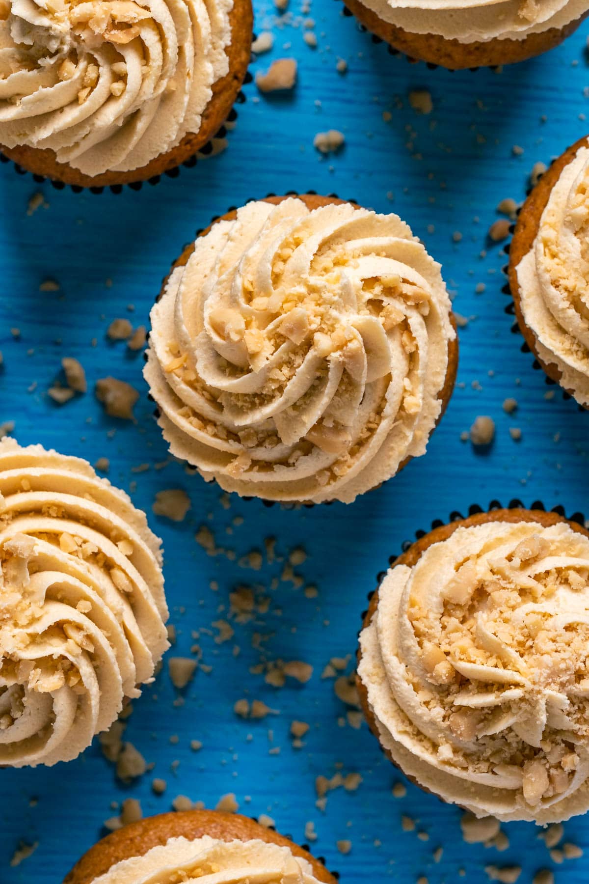 Cupcakes frosted with vegan peanut butter frosting and topped with crushed peanuts.