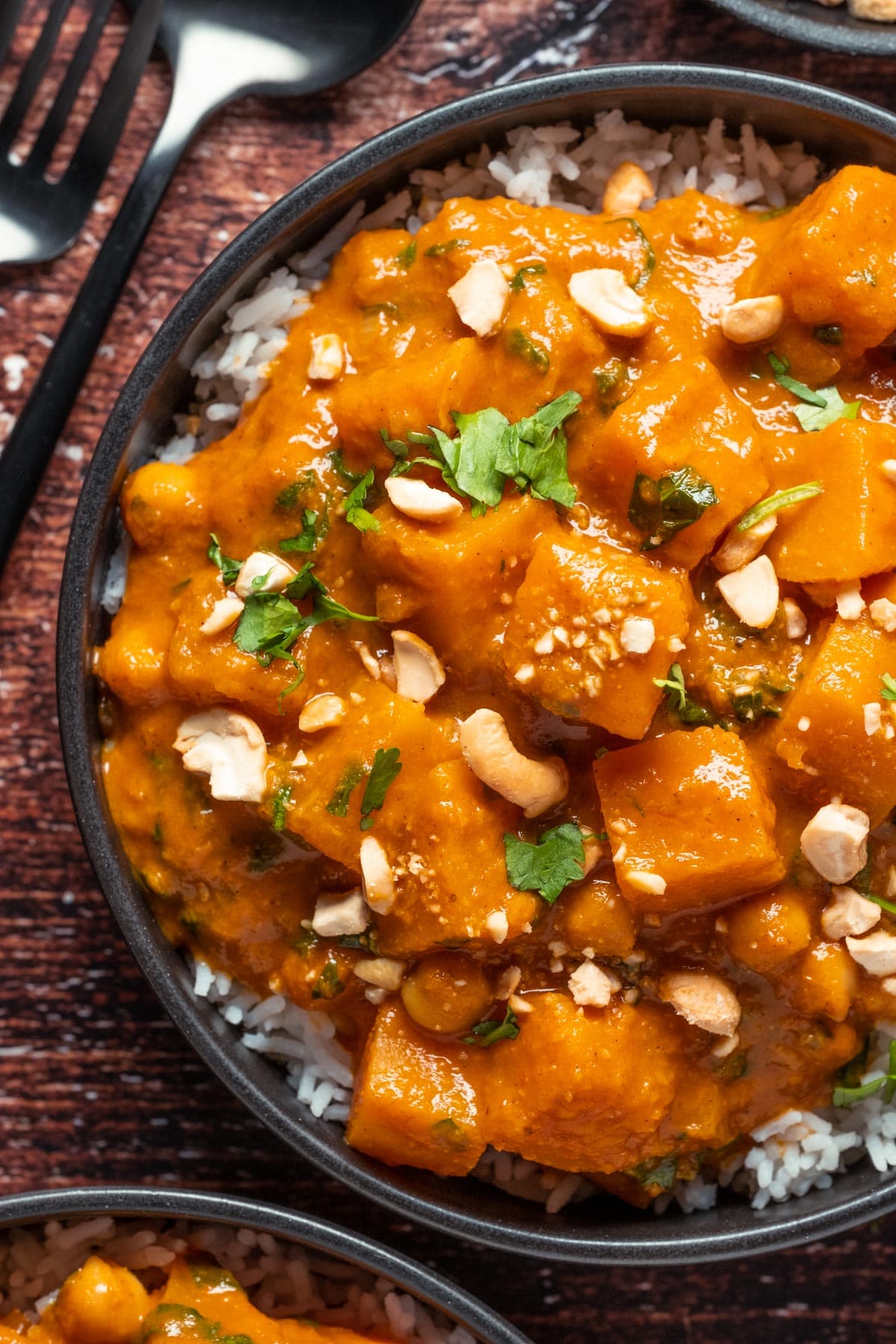 Vegan butternut squash curry with rice in a black bowl.