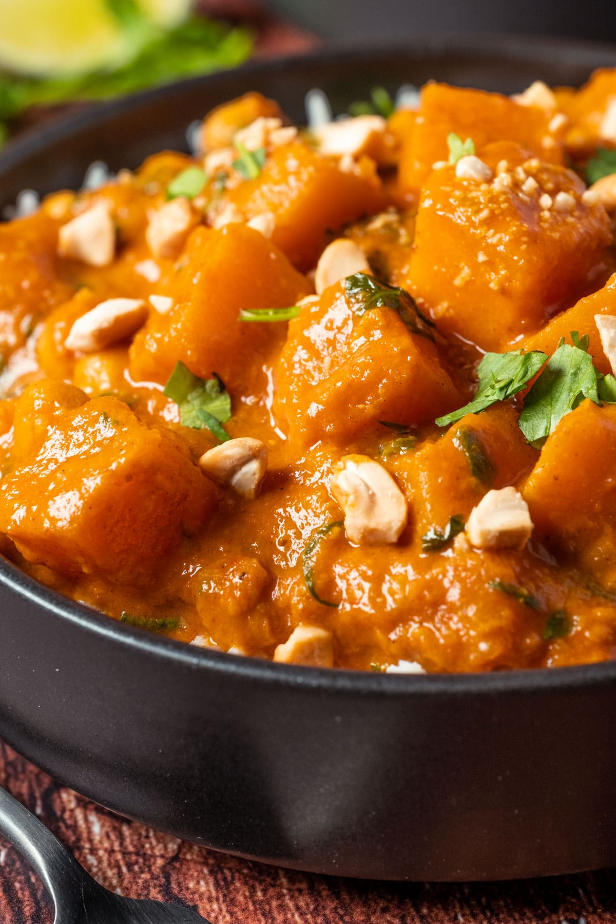 Veganes Butternusskürbis-Curry mit Reis in einer schwarzen Schüssel.