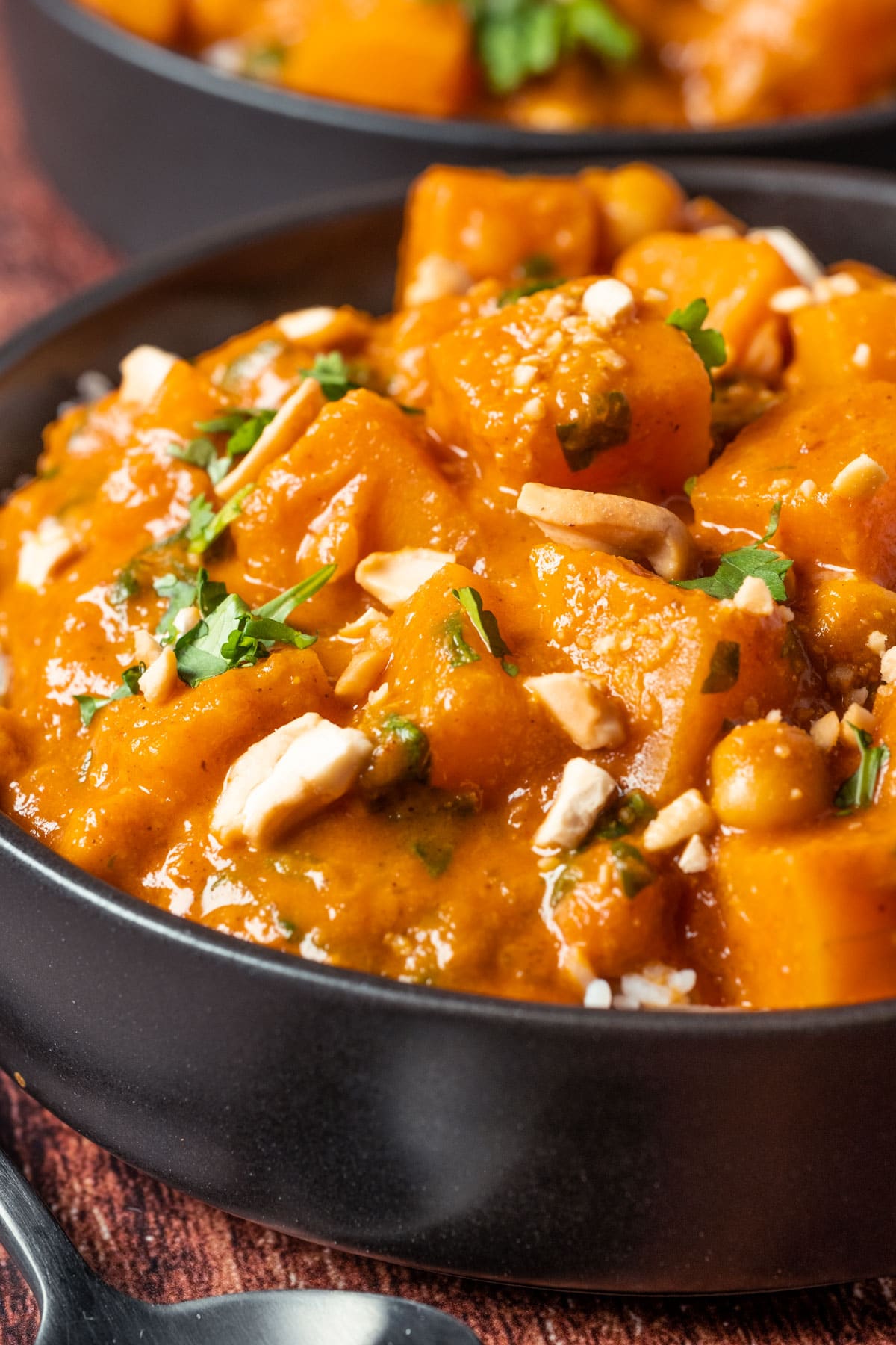 Veganes Butternusskürbis-Curry und Reis in einer schwarzen Schüssel.