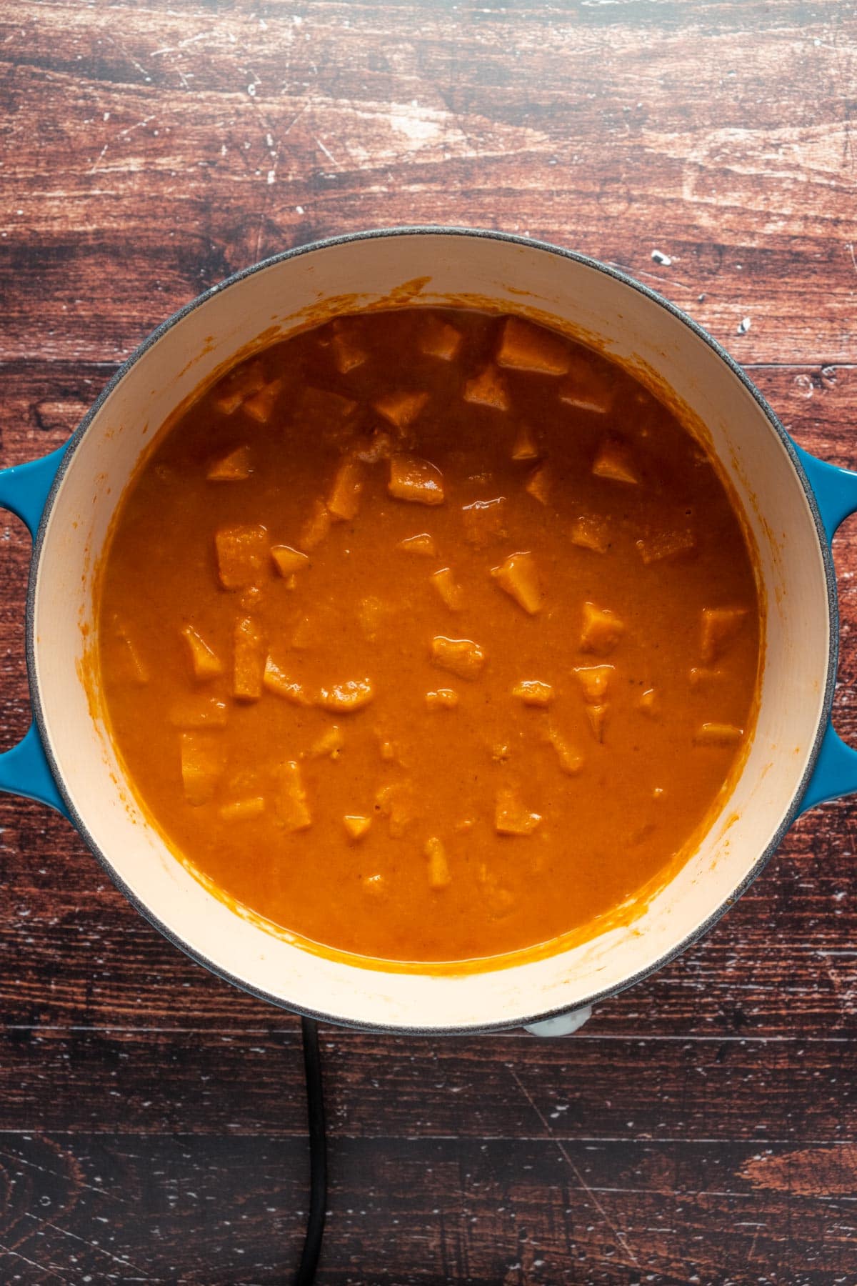 Butternusskürbis-Curry in einem Keramiktopf kochen.